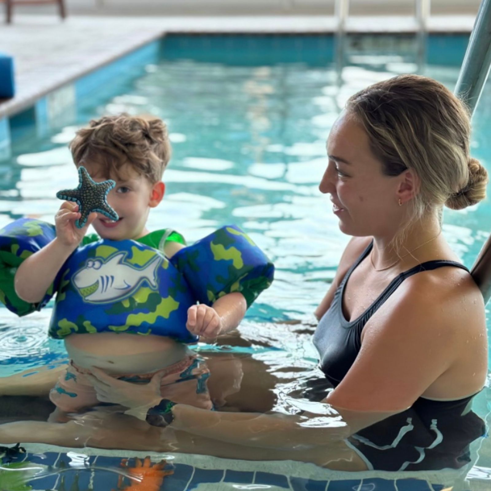 child holds up a starfish toy during aquatic therapy