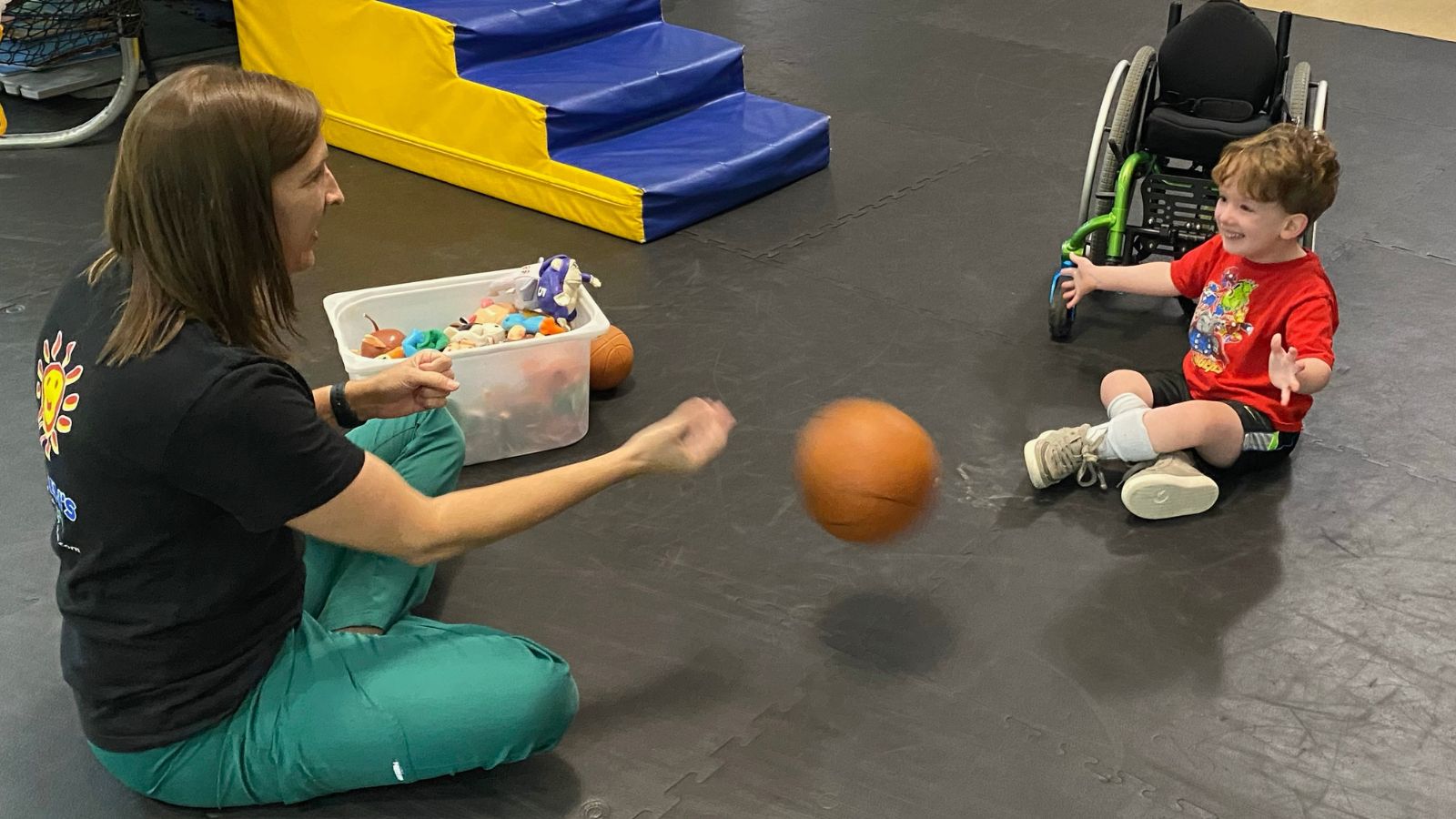 therapist tosses a ball to a boy during intensive therapy